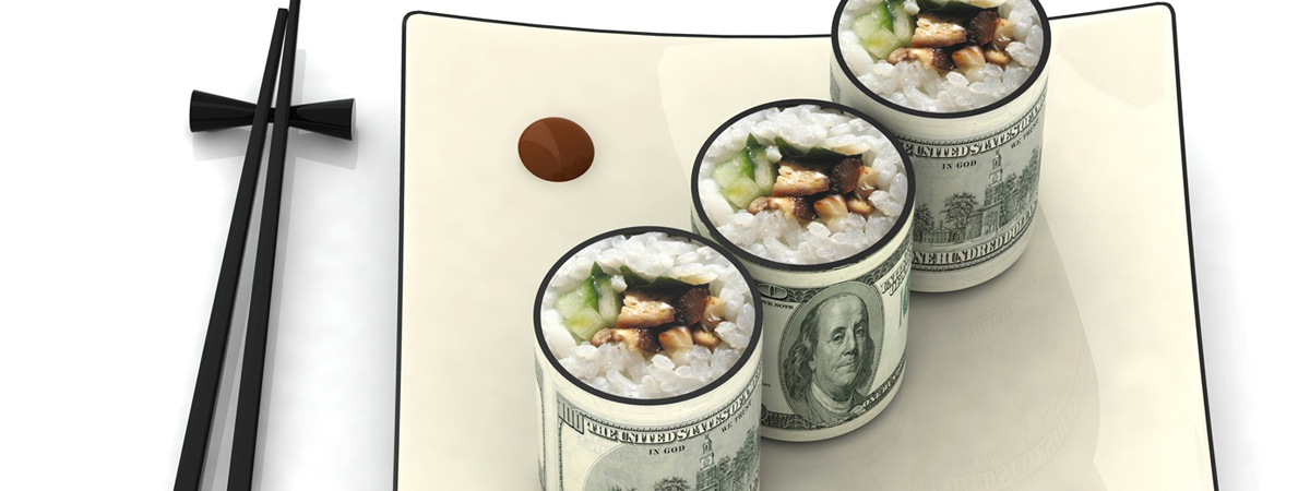 Sushi-style rolls made to look like rolled currency with rice and vegetables on top, placed on a white plate with chopsticks